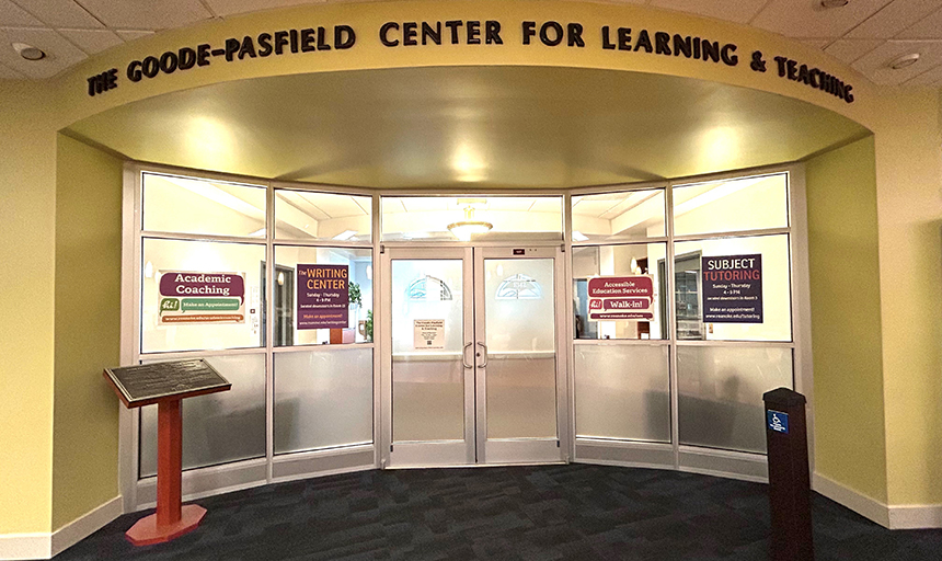 Entrance to the Goode-Pasfield Center for Learning & Teaching, with yellow walls and posters in the window advertising subject tutoring, academic coaching, writing help and more.