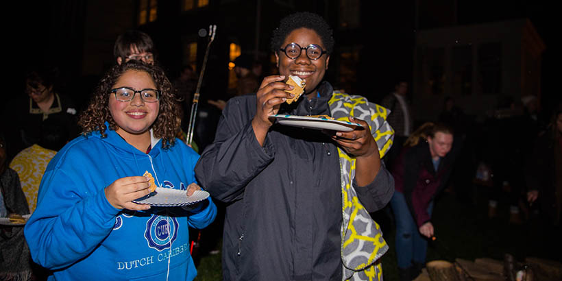 Students eating s'mores at the bonfire with Joseph McGill