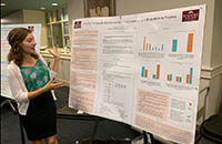 Student standing explaining research of poster