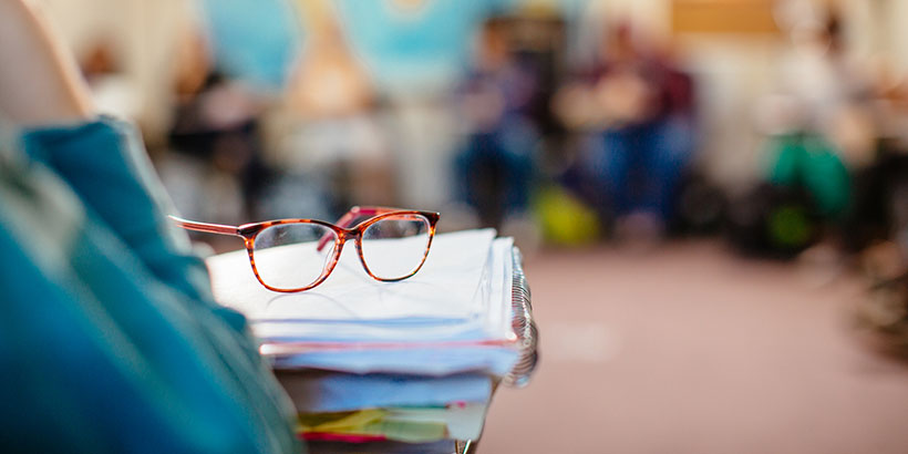 Closeup on a pair of glasses on top of a stack of open notebooks