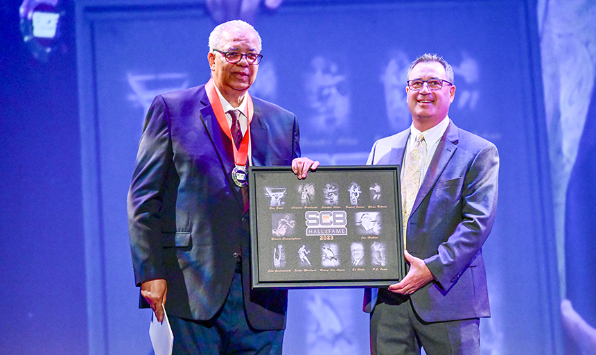 Frankie Allen (left) accepts a plaque during the Small College Basketball Hall of Fame induction ceremony.