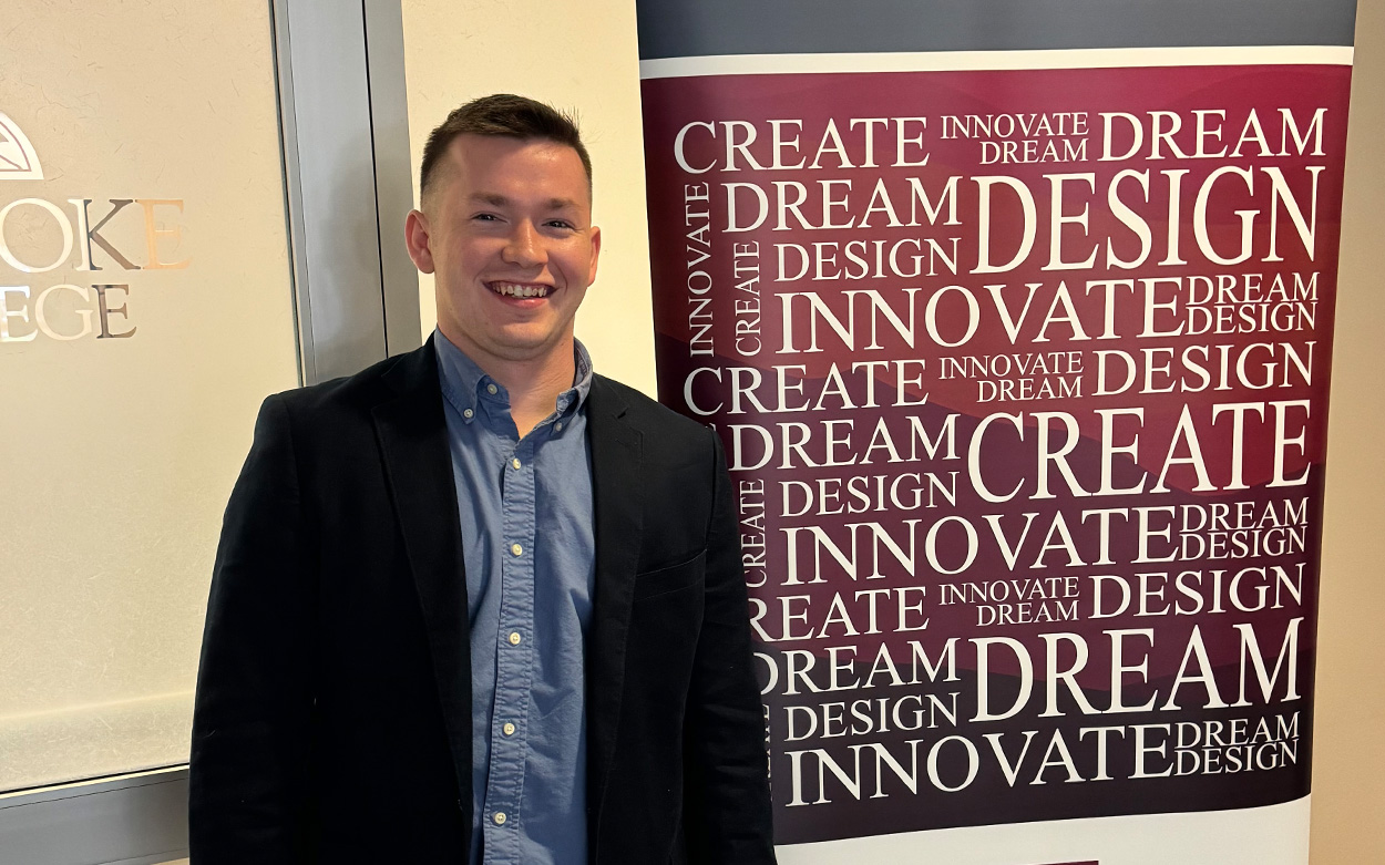 Student smiling next to Center for Leadership and Entrepreneurial Innovation sign imprinted with words like: Create. Dream. Innovate.