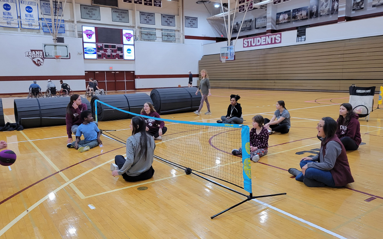 Children and volunteers playing floor volleyball in a Roanoke College gym