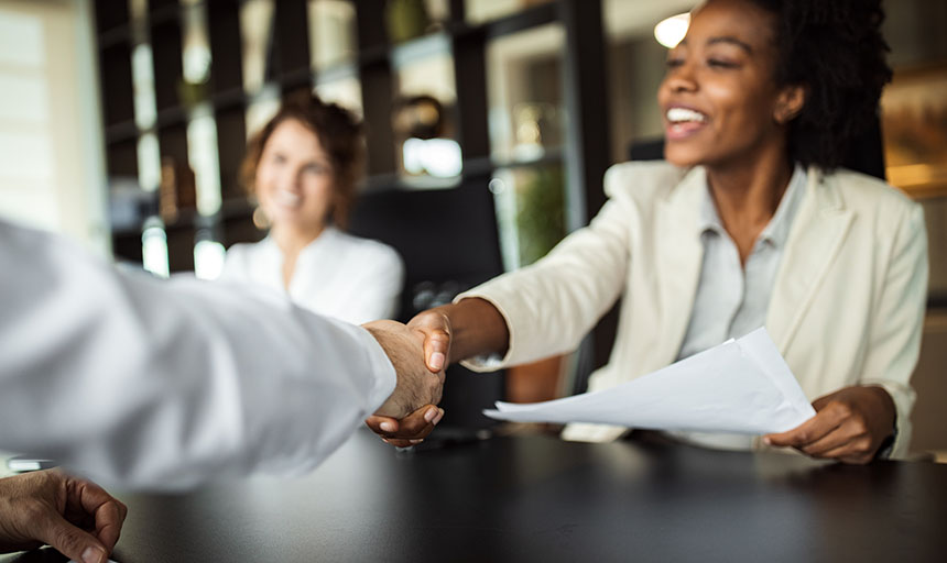 Job candidate shakes hands with someone at a table