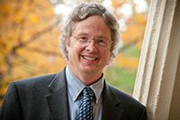 A smiling mal professor standing in front of trees