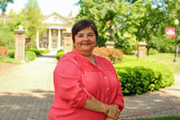 A picture of a smiling, female professor in front of the Roanoke College Administration building