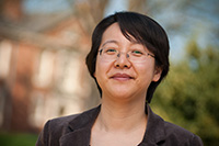 A smiling female professor standing in front of a building on the Roanoke College campus