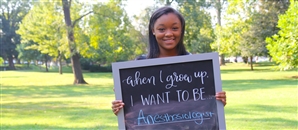 A student holds a sign announcing her hope of becoming an anesthesiologist after graduation