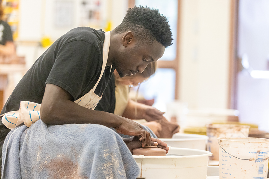 student throwing pottery