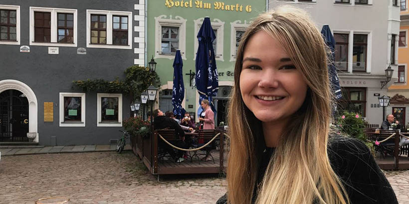 A student smiling in front of some buildings in Leipzig