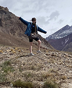 student poses with mountains behind her