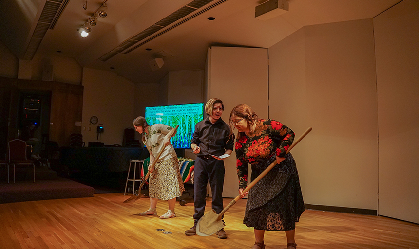 Three students perform on a stage