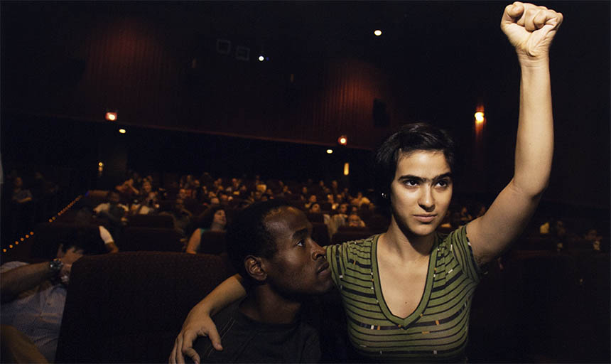 a woman with her arm around a black man and her fist raised up in the air