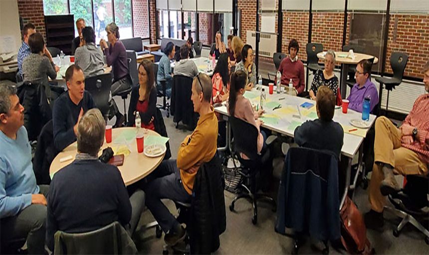 Faculty and staff interacting and talking at tables.