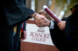 Student and president shaking hands during graduation ceremony 