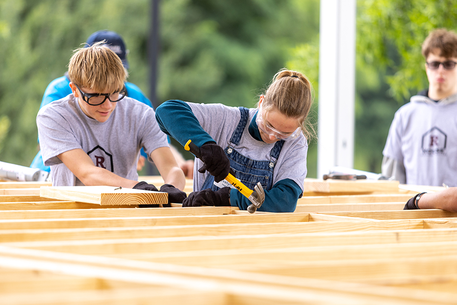 Students hammering on a house frame