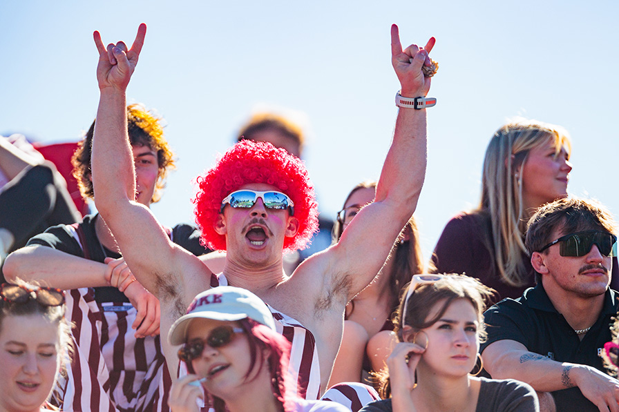 Student with arms up at a game cheering