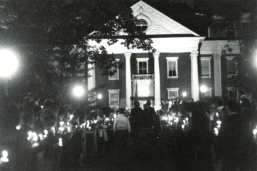 historic image of administration building with people holding candles outside