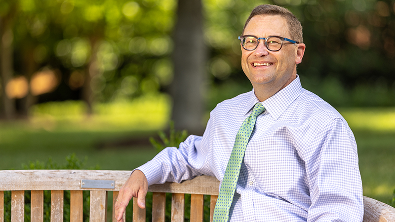 President Frank Shushok at a bench on the front quad