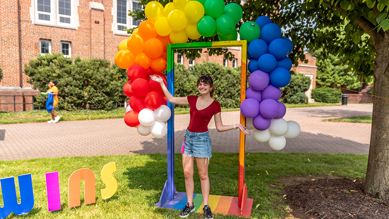 Student under rainbow balloons