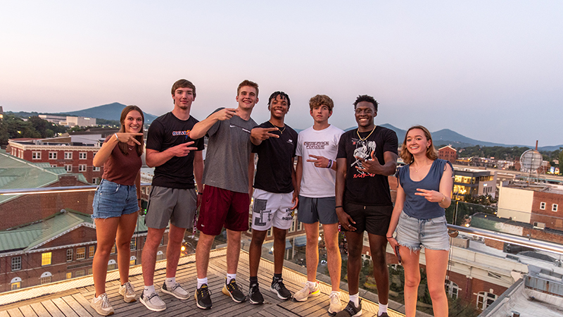 Group of students in downtown Roanoke on a rooftop patio with the mountains beyond