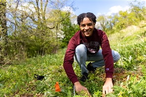 Student smiles while kneeling down in the grass