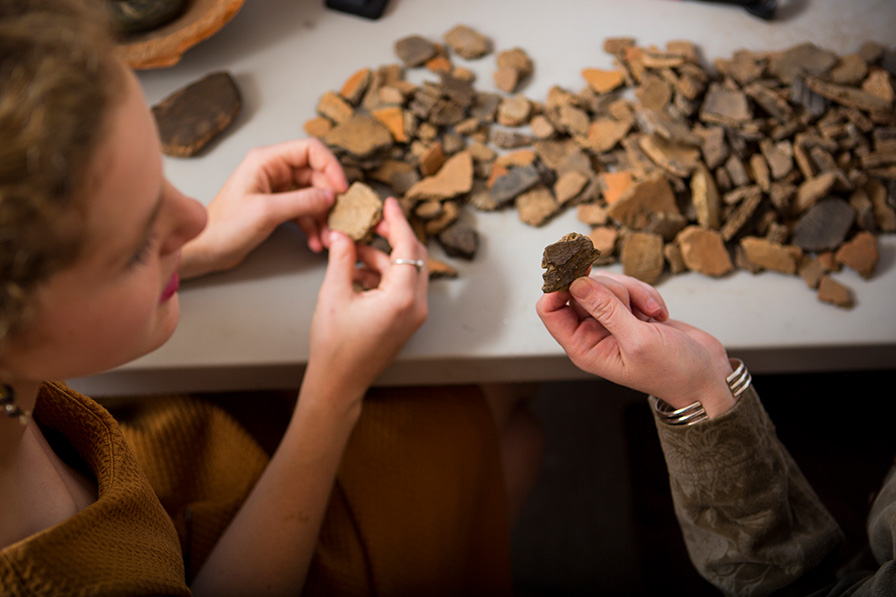 student and professor handle artifacts