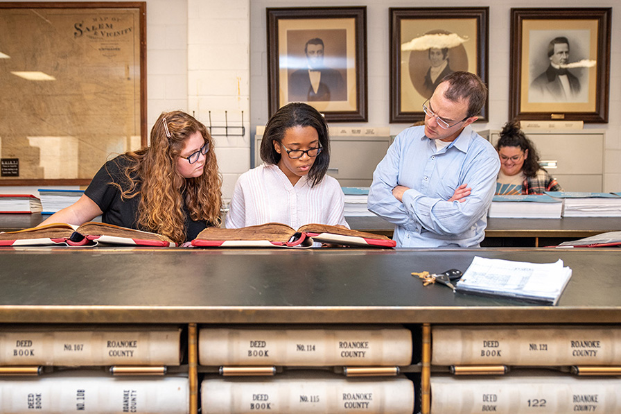 students and professor pore over archival books