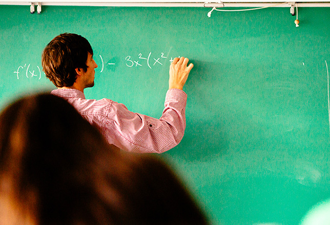 professor writing equation on chalkboard