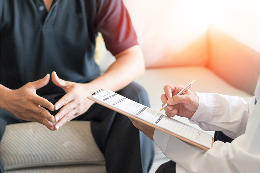 Closeup on hands of clinician taking notes on clipboard while talking with patient