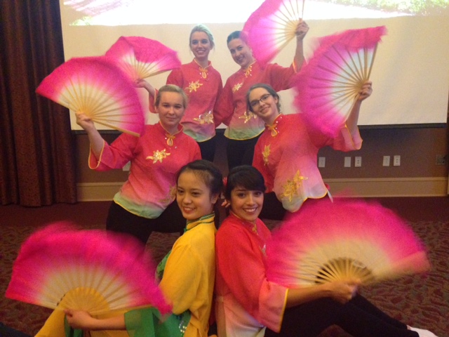 International students dancing in costumes with large fans