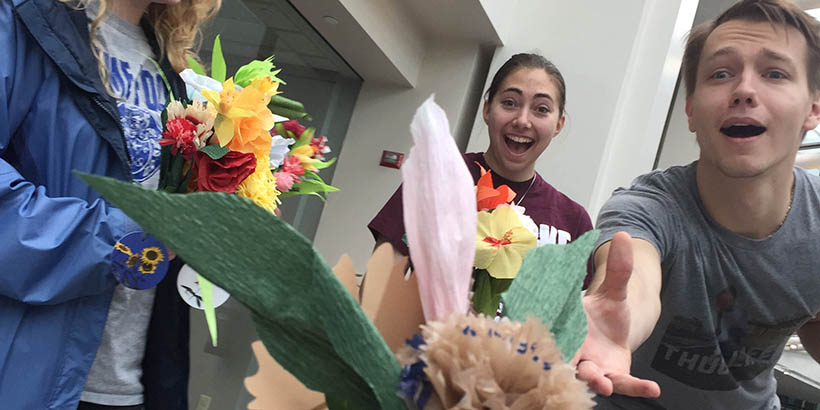 Students handing out paper flower bouquets at a hospital