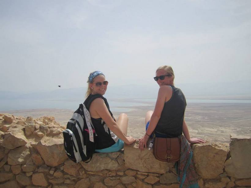 Students sitting on a wall overlooking a city