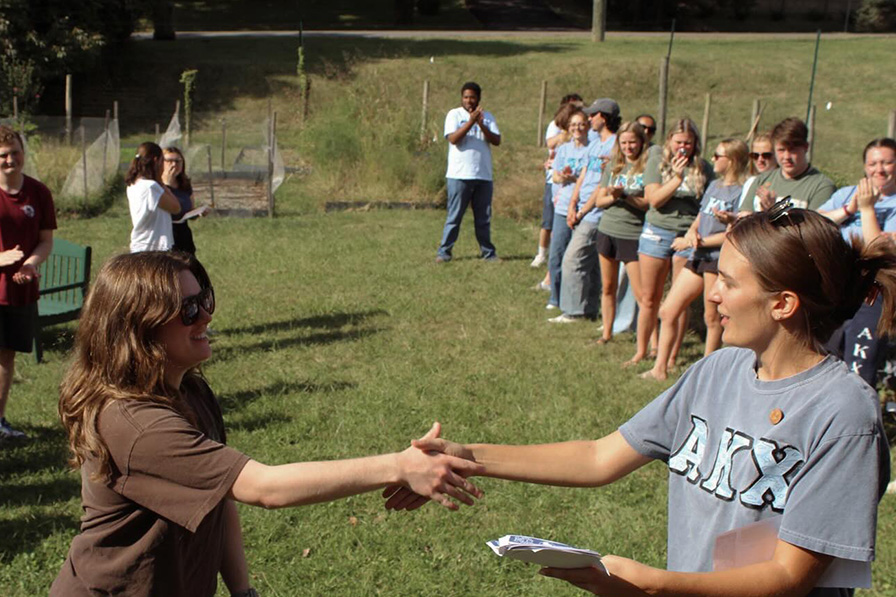 Photo of two Alpha Kappa Chi members shaking hands