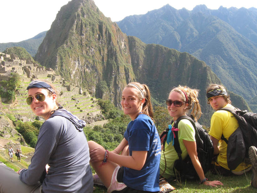 Students sitting on a hill by a mountain range in a Latin American country