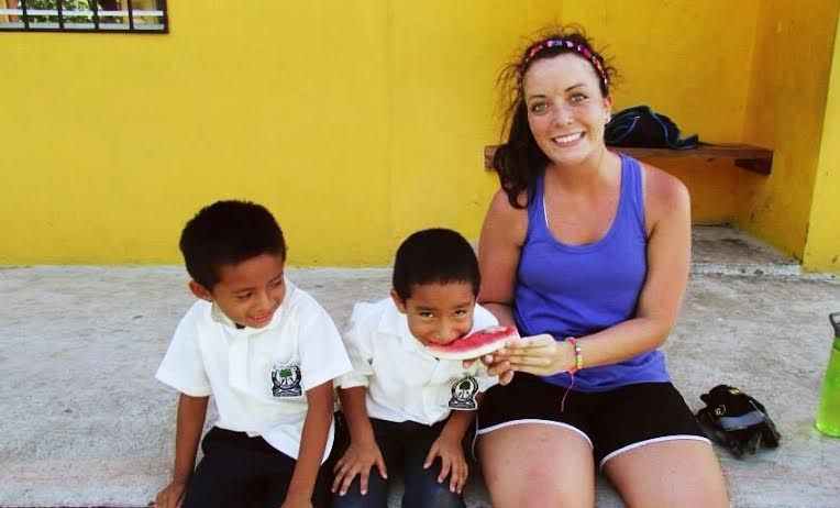 A student with two children, one of which is eating watermelon, in a Latin American country