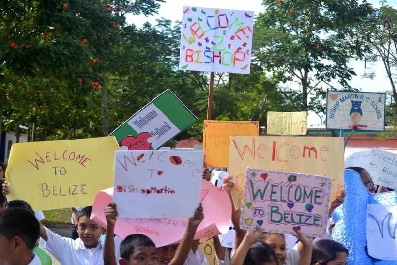 Community members holding up signs reading "Welcome to Belize"