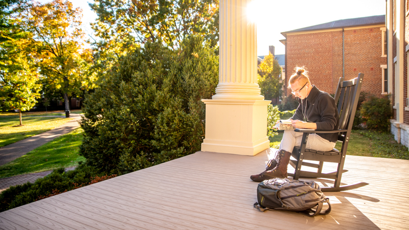 Student reading on the porch of the Administration Building