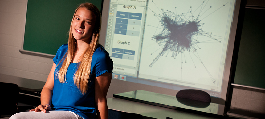 student sits on desk in front of mathematics on screen