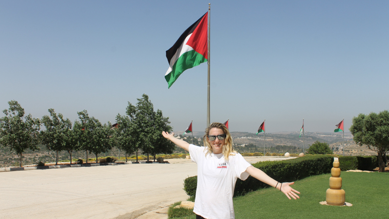 Student in front of a Palestinian flag