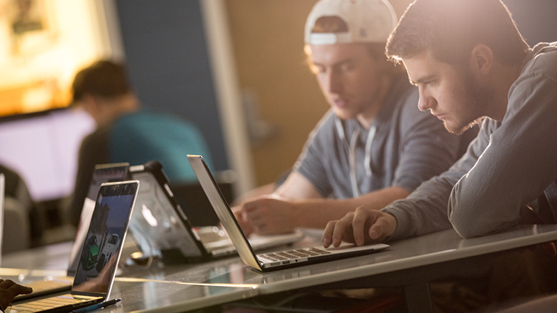 two students looking at a laptop