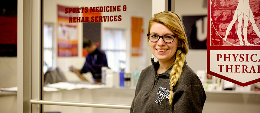 Student in front of a door reading "Sports medicine and rehab services"
