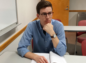 Christian Weisenbacher  sits at a desk with hand to his chin. 