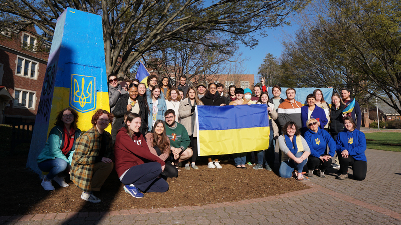 Students showing support for Ukraine with flags next to the painted blue and yellow Rock