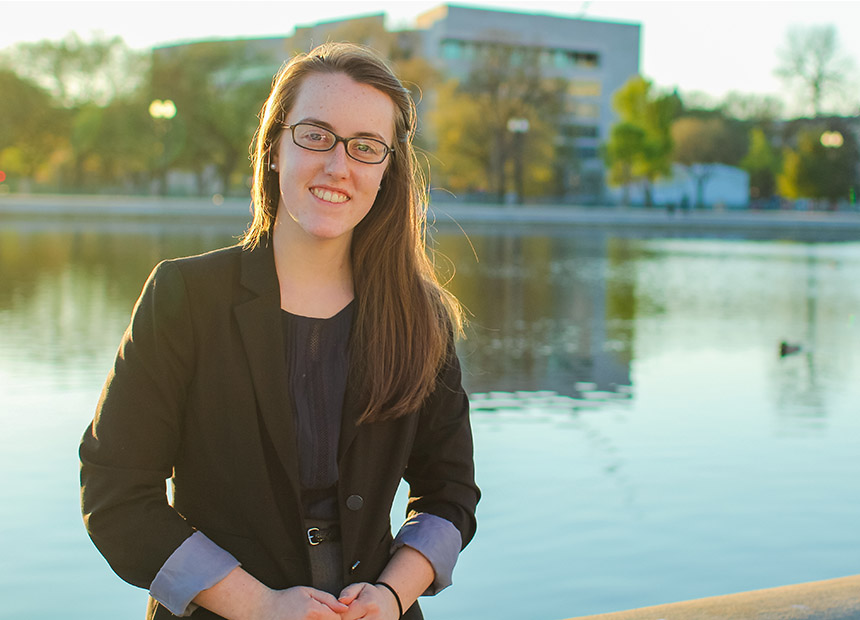 Student posing for a photo by the reflecting pool