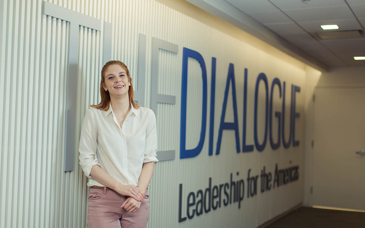 Bentleigh Asboth ’20 standing in front of a wall that reads "The Dialogue, Leadership for the Americas"