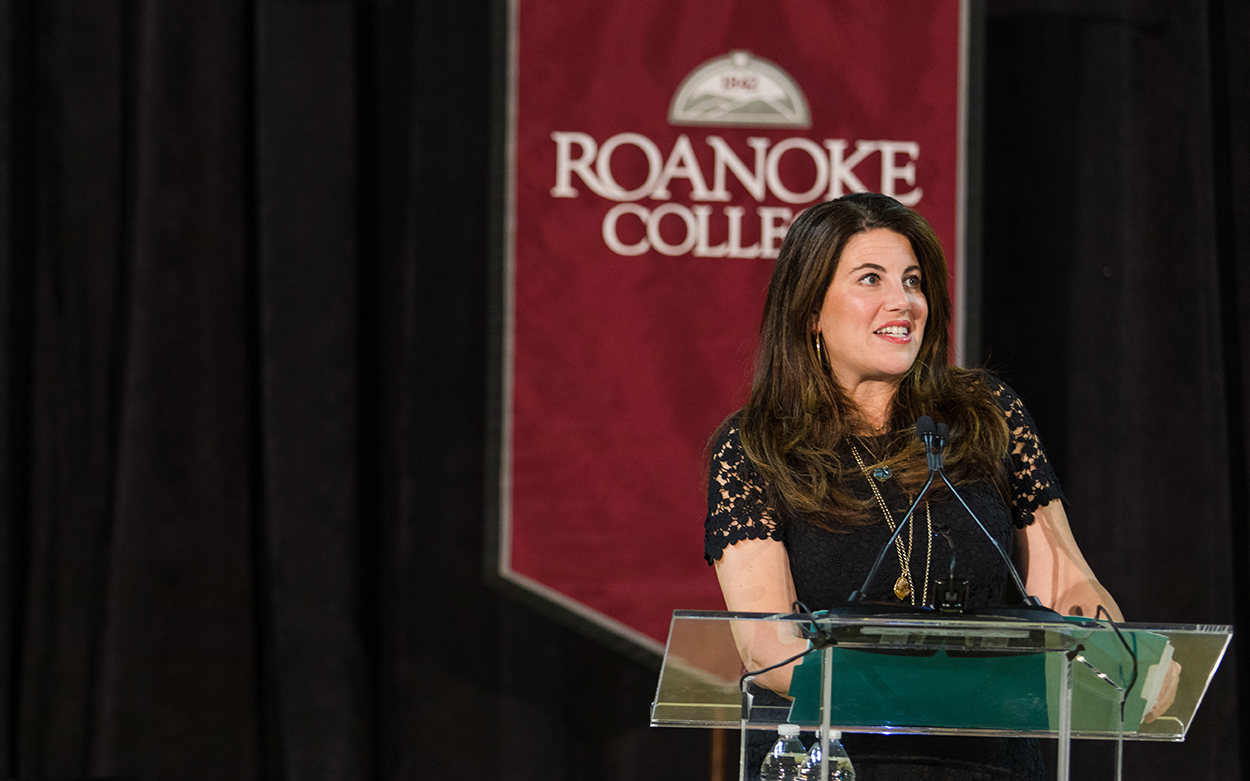 Monica Lewinsky speaking at a podium in front of a Roanoke College banner