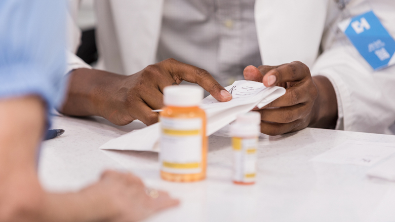 Close-up of pharmacists hands next to medication bottles