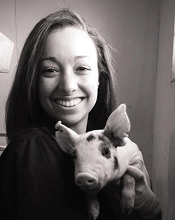 photo of Tyler Barnes smiling while holding a small pig