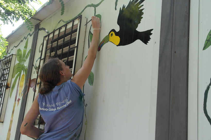 Student painting a mural on the side of a building